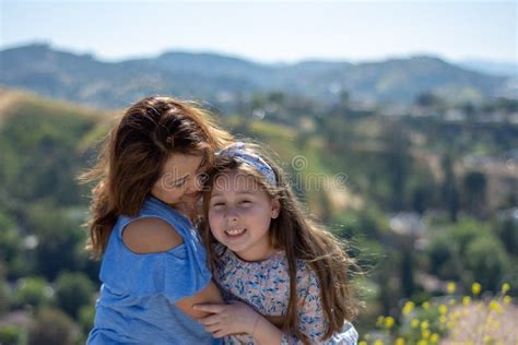 Madre E Hija De Latina Que Sonr En Y Que R En En Una Colina Delante De Las Flores Amarillas