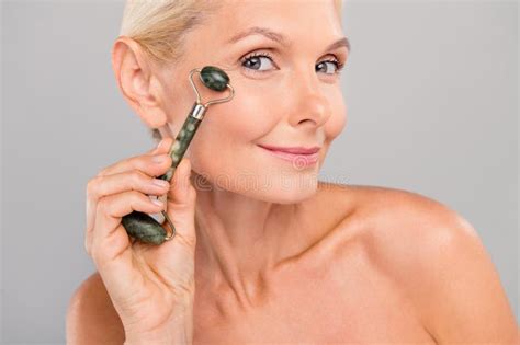 Photo Of Charming Pretty Senior Lady Nude Shoulders Doing Under Eyes Roller Massage Isolated