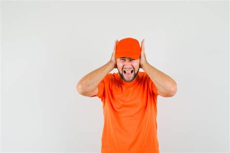 Free Photo Delivery Man Holding Hands On Ears In Orange T Shirt Cap