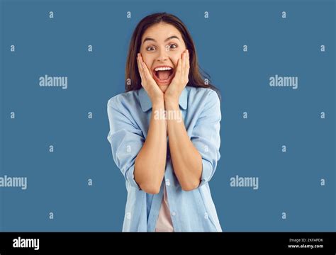 Beautiful Brunette Screams With Joy And Happiness Holding Her Cheeks With Her Hands Stock Photo