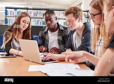 Group Of College Students Collaborating On Project In Library Stock