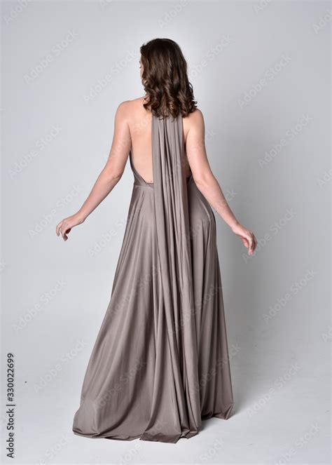 Portrait Of A Pretty Brunette Girl Wearing A Long Silver Evening Gown Full Length Standing Pose
