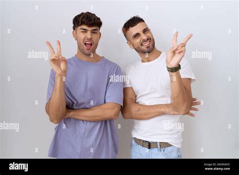 Homosexual Gay Couple Standing Over White Background Smiling With Happy Face Winking At The
