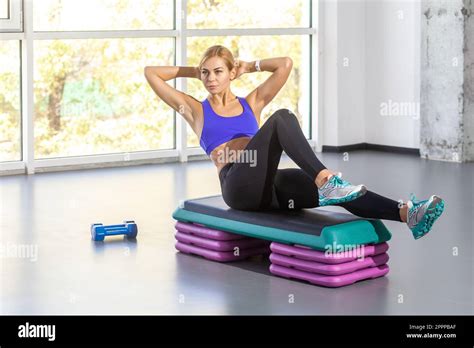 Portrait Of Sporty Athletic Woman With Blonde Hair Wearing Tight Sportswear Sitting On Step