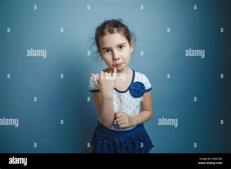 A Girl Of Seven European Appearance Brunette Licks A Finger On A Gray Background Taste Stock