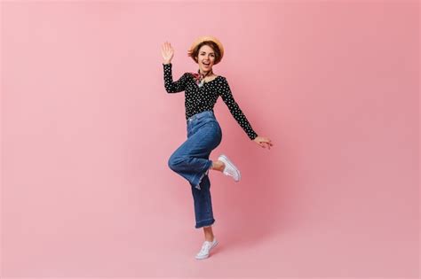 Merveilleuse Jeune Femme Au Chapeau De Paille Sautant Sur Un Mur Rose