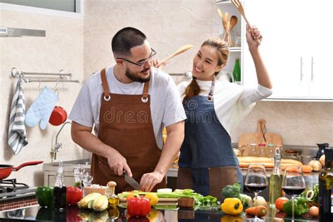 Loving Young Asian Couple Cooking In Kitchen Making Healthy Food Together Feeling Fun Stock