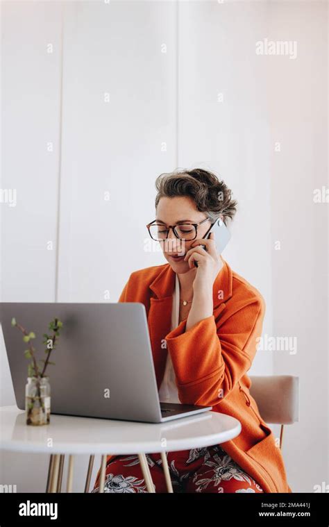 Business Woman Speaking On A Phone Call While Working On A Laptop In A Cafe Mature