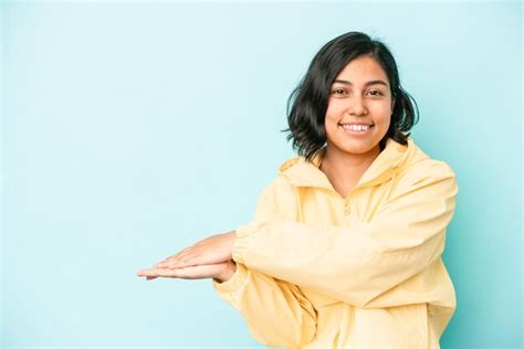 Jovem mulher latina isolada em um fundo azul segurando um espaço de cópia na palma da mão