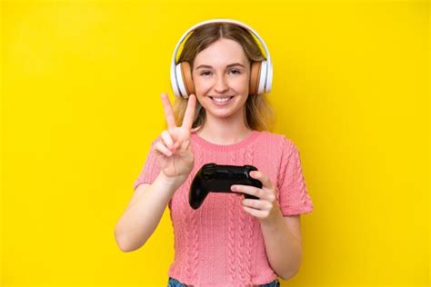 Blonde jeune fille anglaise jouant avec un contrôleur de jeu vidéo isolé sur fond jaune Photo