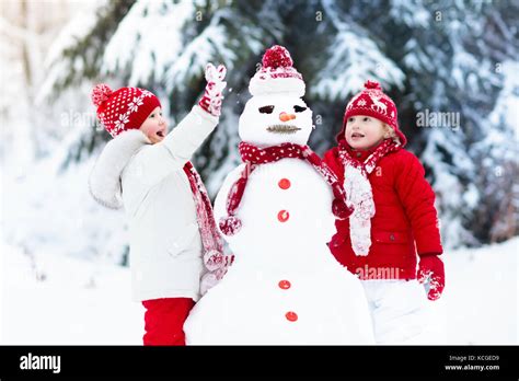 Children build snowman. Kids building snow man playing outdoors on ...