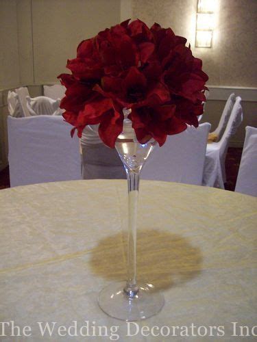 A Vase Filled With Red Flowers Sitting On Top Of A White Tablecloth