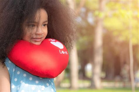 Premium Photo Cute Girl With Curly Hair Holding Heart Shape Pillow