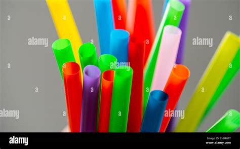 Multi Colored Plastic Straws In A Jar In Front Of A Grey Background