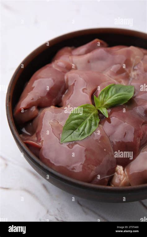 Bowl With Raw Chicken Liver And Basil On White Textured Table Closeup