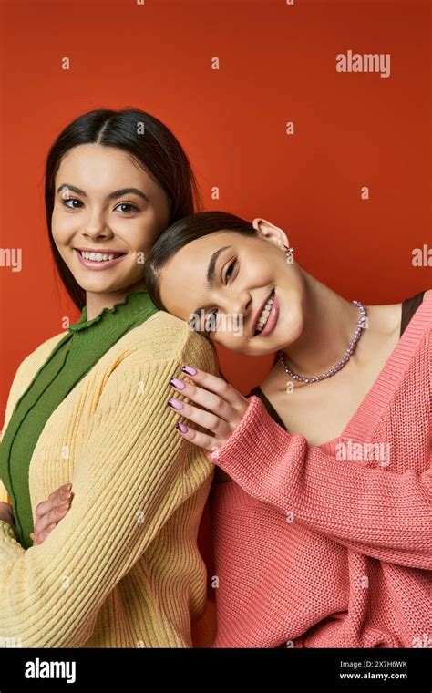 Two Pretty Brunette Teenage Girls Wearing Casual Attire Hugging Each Other In Front Of A Vivid