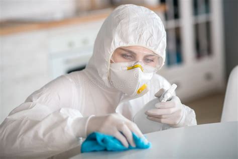 Mujer Con Ropa De Trabajo Blanca Y Guantes Protectores Desinfectando La