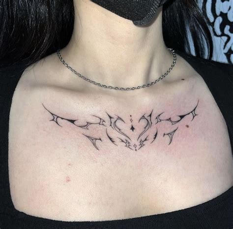 A Woman Wearing A Black Shirt Has A Tattoo On Her Chest