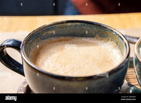 Blue Ceramic Cup Of Hot Cappuccino With Foam On Wooden Cafe Table Beautiful Latte With Bubble