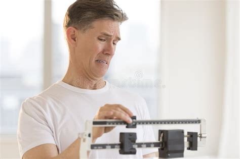 Hombre Preocupante Que Usa La Escala Del Peso En El Gimnasio Foto De