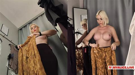Une blonde aux seins énormes essaye des vêtements dans un centre