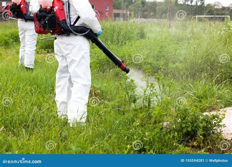 Man In Protective Workwear Spraying Herbicide On Ragweed In An Urban