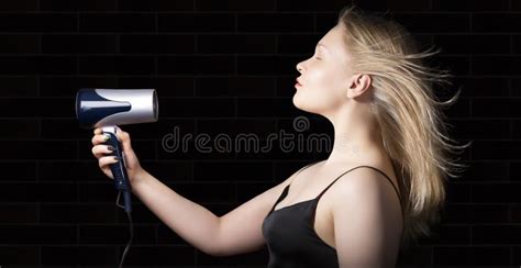 Blonde Girl Dries Her Hair With A Hair Dryer On A Black Background Stock Photo Image Of