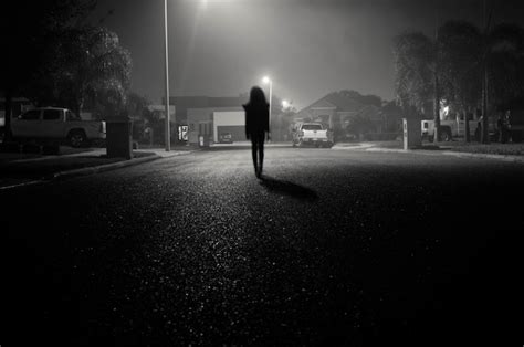 Chica Caminando En Una Calle Urbana Por La Noche Bajo Farolas Foto Gratis