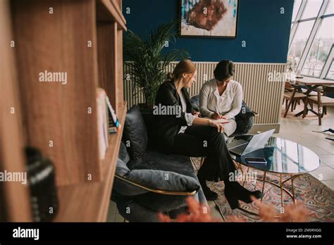 Brunette Business Girl Writing Notes While Laughing With Her Colleague At The Cafe Stock Photo