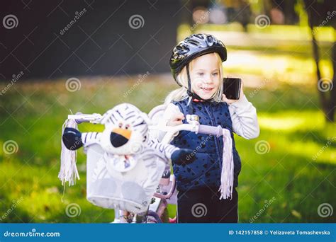 Het Grappige Blonde Van Het Kind Kaukasische Meisje In Een Fietshelm Dichtbij Een Purpere Fiets