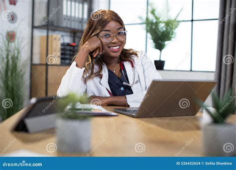 African American Woman Doctor In White Coat And Stethoscope Sitting At