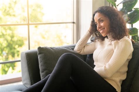 Mulher latina sorrindo e sentado no sofá Foto Premium