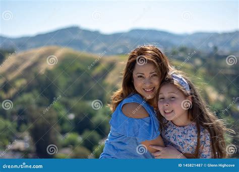M E E Filha De Latina Que Sorriem E Que Riem Em Um Monte Na Frente Das Flores Amarelas Imagem De