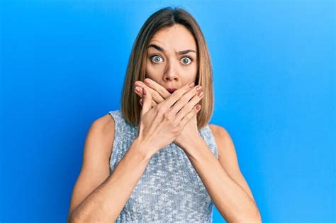 Jeune femme blonde caucasienne portant un t shirt décontracté choqué couvrant la bouche avec les