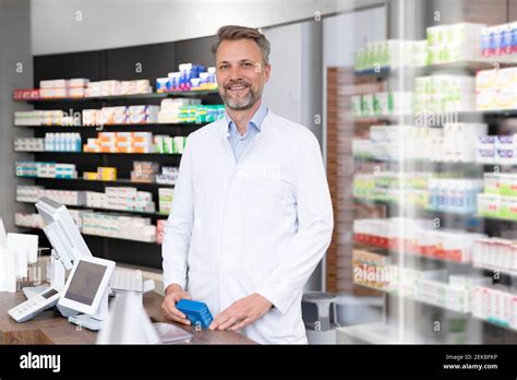 Smiling Mature Pharmacist With Medicine Box Standing At Pharmacy Checkout Stock Photo Alamy