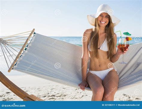 Pretty Blonde Wearing Bikini And Sunhat Sitting On Hammock With Stock
