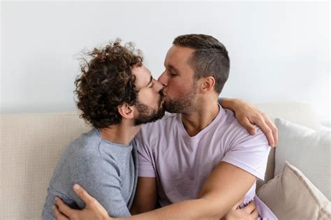 Beau couple gay s embrassant assis dans leur salon à la maison Deux jeunes amants romantiques s