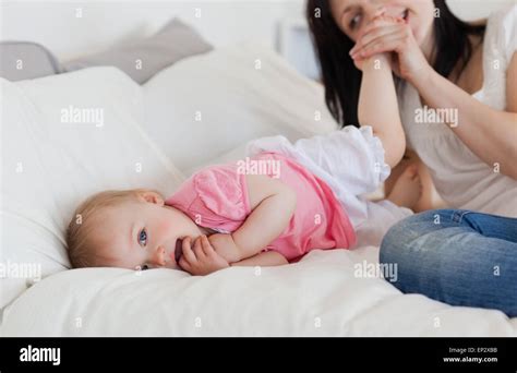 Good Looking Brunette Female Playing With Her Baby While Lying On A Bed Stock Photo Alamy