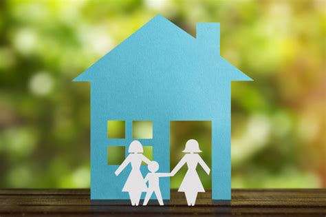 Figura de papel de um casal gay de mãos dadas o filho adotivo casa azul e fundo desfocado