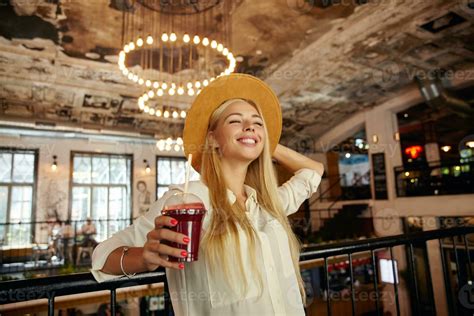 Pleased Attractive Long Haired Blonde Lady Standing Over Restaurant Interior Leaning On Iron