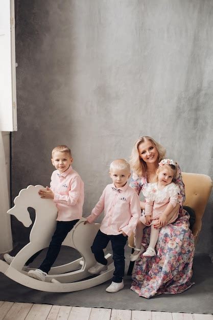 Wunderschöne blonde Mutter im Kleid umarmt mit hübscher Tochter während zwei Söhne in ähnlicher