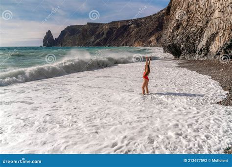 A Beautiful And Brunette In A Red Swimsuit On A Pebble Beach Running