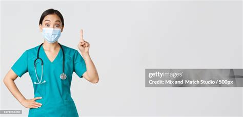 Portrait Of Female Doctor Wearing Surgical Mask While Standing Against