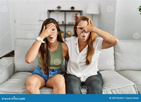 Mother And Daughter Together Sitting On The Sofa At Home Peeking In