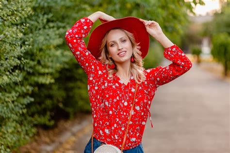 Schöne attraktive stilvolle blonde lächelnde Frau in strohrotem Hut und Bluse Sommermode Outfit