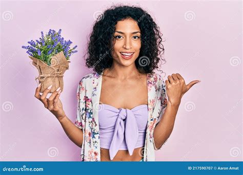 Jovem Latina Segurando Uma Planta Lavanda Apontando O Polegar Para O Lado Sorrindo Feliz A