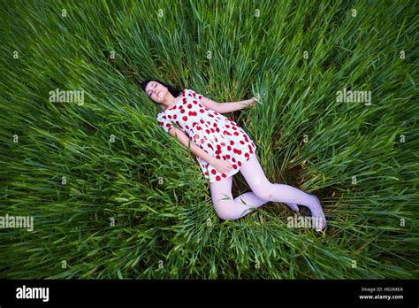 Brunette In A Bright Dress Lying In The Tall Grass Stock Photo Alamy