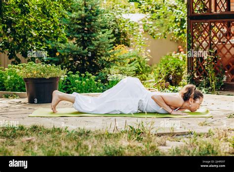 Young Woman Practices Yoga In The Garden Surya Namaskar Four Point
