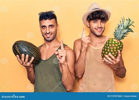 Joven Pareja Gay Con Ropa De Verano Sosteniendo Melón Y Piña Sonriendo Con Una Idea O Pregunta