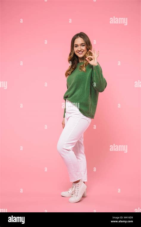 Full Length Image Of Smiling Blonde Woman Wearing In Green Sweater Showing Ok Sign And Looking